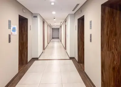 an empty corridor of an office building with wooden doors at Cozy Studio Pool & Gym Near Burj Khalifa & Racecourse views in Dubai