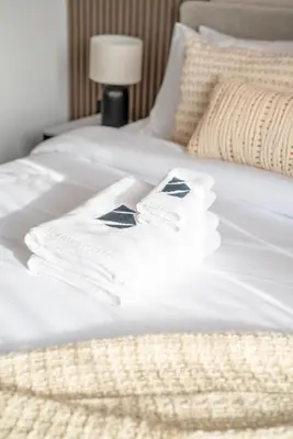 two white towels are sitting on a bed at New Family-Friendly 2BR with Gym and Pool and Sauna in Dubai