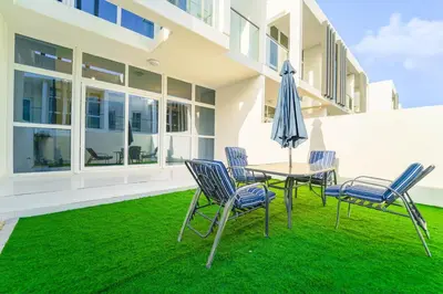 a patio with a table and chairs and an umbrella at Cozy 2BR Villa in Damac Hills 2 by deleguest in Dubai