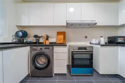 a kitchen with a washing machine and a washer at Cozy 2BR Villa in Damac Hills 2 by deleguest in Dubai