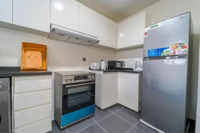 a kitchen with white cabinets and a stainless steel refrigerator at Cozy 2BR Villa in Damac Hills 2 by deleguest in Dubai