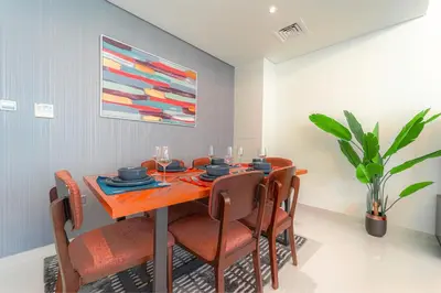 a dining room table with chairs and a painting on the wall at Cozy 2BR Villa in Damac Hills 2 by deleguest in Dubai