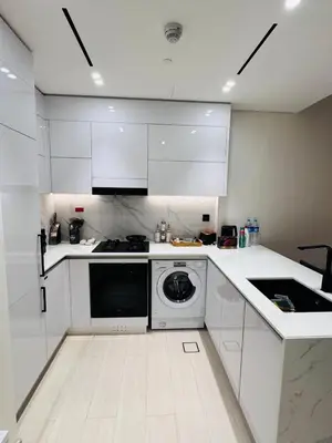 a kitchen with white cabinets and a washing machine at Elegant 1BR Apt in JVC Dubai with Spacious Balcony & City Views in Dubai