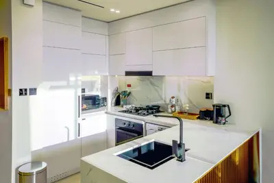 a kitchen with white cabinets and a sink at Elegant 1BR Apt in JVC Dubai with Spacious Balcony & City Views in Dubai