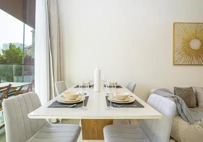 a dining room with a white table and chairs at Spacious 3BR Apartment in JVC Dubai Modern & Cozy Stay in Dubai