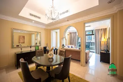 a living room with a dining table and a bedroom at Souk Al Bahar - Burj Khalifa - Dream View Holiday Home Rental in Dubai