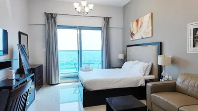 a bedroom with a bed and a couch and a window at High Floor - Bright Elite Studio in Business Bay in Dubai