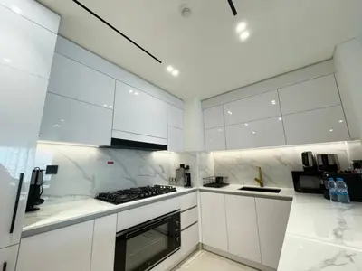 a kitchen with white cabinets and a stove top oven at Brand New Cozy 2br Apartment In Jvc With Balcony in Dubai