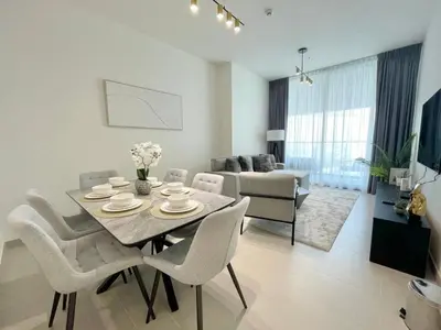a dining room and living room with a table and chairs at Brand New Cozy 2br Apartment In Jvc With Balcony in Dubai