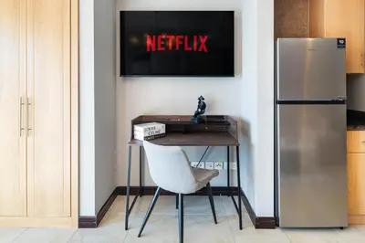 a desk with a chair next to a refrigerator at Stylish JLT Studio Lake View PoolMarina Walk in Dubai