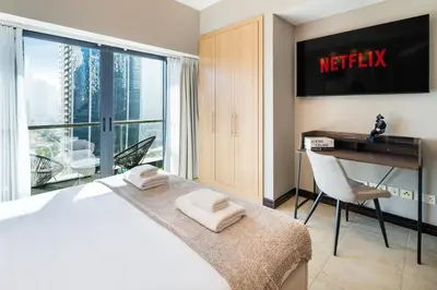 a hotel room with a bed and a desk and a window at Stylish JLT Studio Lake View PoolMarina Walk in Dubai