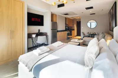 a bedroom with a white bed and a kitchen at Stylish JLT Studio Lake View PoolMarina Walk in Dubai