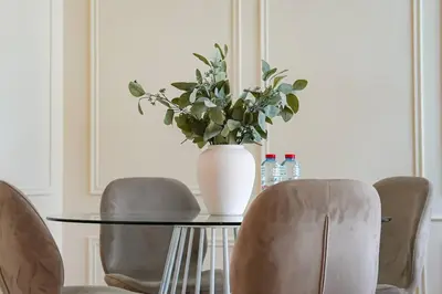 a table with a vase of flowers and chairs at Luxe JLT 1BR Apt Gym Pool & Stunning Views in Dubai