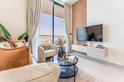 a living room with a tv and two chairs at City Views 1BR Near Community Park with Private Balcony, Binghatti House, Jumeirah Village Circle by Deluxe Holiday Homes in Dubai