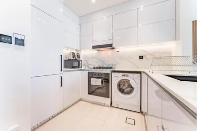 a white kitchen with a washer and dryer at City Views 1BR Near Community Park with Private Balcony, Binghatti House, Jumeirah Village Circle by Deluxe Holiday Homes in Dubai