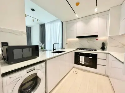 a white kitchen with a washing machine and a microwave at Premium 2br Apartment With Private Pool In Jvc in Dubai