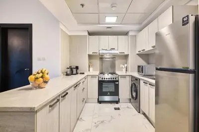 a kitchen with a refrigerator and a bowl of fruit on the counter at Family-Friendly 2BR Apartment in Dubai South at MAG-565 near EXPO and Al Maktoum Airport DWC in Dubai