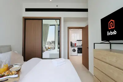 a hotel room with a white bed and a kitchen at Livbnb-Urban Getaway 1BHK with JVC Skyline View in Dubai