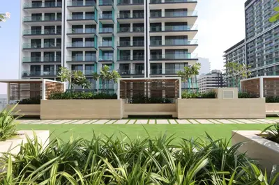 a park in front of a tall building at Livbnb-Urban Getaway 1BHK with JVC Skyline View in Dubai