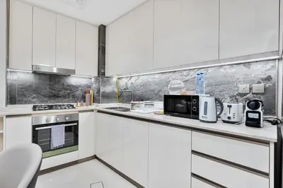 a white kitchen with white cabinets and appliances at Stylish New Apt, Minutes from Downtown Dubai in Dubai