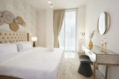 a white bedroom with a large bed and a desk at Modern 2 bedroom in Binghatti Crescent JVC- Truebleu vacation homes in Dubai