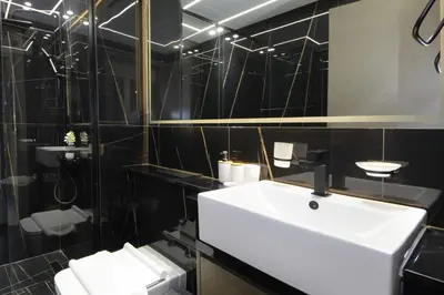a bathroom with a white sink and black tiled walls at Modern 2 bedroom in Binghatti Crescent JVC- Truebleu vacation homes in Dubai