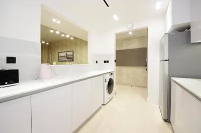 a white kitchen with a washer and dryer at Modern 2 bedroom in Binghatti Crescent JVC- Truebleu vacation homes in Dubai