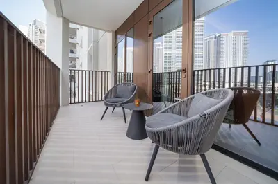 a balcony with two chairs and a table on it at Luxury 2-Bed Retreat with Stunning Creek Views in Dubai