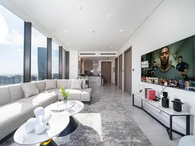 a living room with a white couch and a tv at Brand New Business Bay 1 Bed with Burj Khalifa and Canal Views in Dubai