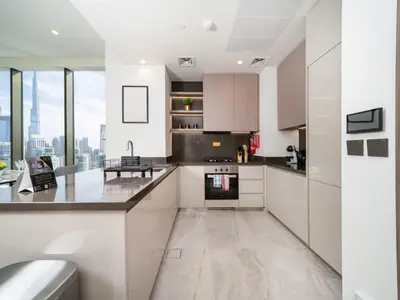 a kitchen with white cabinets and a large window at Brand New Business Bay 1 Bed with Burj Khalifa and Canal Views in Dubai