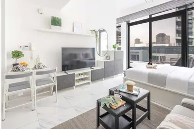 a white living room with a bed and a tv at Frank Porter - Serenity Lakes 5 in Dubai