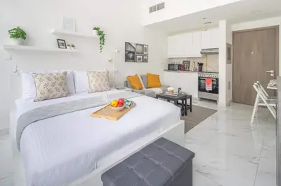a white bedroom with a large bed and a living room at Frank Porter - Serenity Lakes 5 in Dubai
