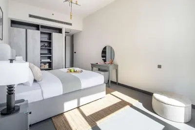 a white bedroom with a bed and a chair at Frank Porter - MBL Royal in Dubai