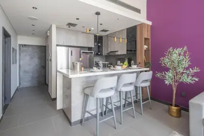 a kitchen with purple walls and a counter with stools at Frank Porter - MBL Royal in Dubai