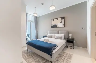 a bedroom with a large bed with a blue blanket at HAVN - 1 Bed in Damac Hills 1, Golf Course View in Dubai