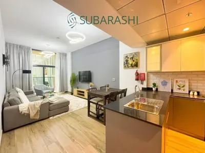 a kitchen and living room with a couch and a table at Stylish 1BR Apartment in JVC in Dubai