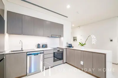 a kitchen with stainless steel appliances and wooden cabinets at LUX The Grande Signature Skyline Suite in Dubai