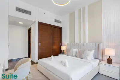 a white bedroom with a large bed and a chair at Chic 1Bedroom with Stunning Marina View in Sparkle in Dubai
