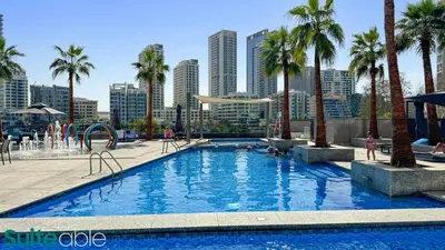 a large swimming pool with palm trees in a city at Chic 1Bedroom with Stunning Marina View in Sparkle in Dubai