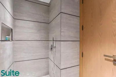 a bathroom with gray walls and a wooden door at Sophisticated Studio in The Autograph in Dubai