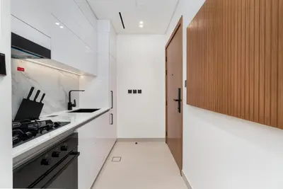 a kitchen with white counters and a stove top oven at Cozy Studio with Sleek Design in JVC in Dubai