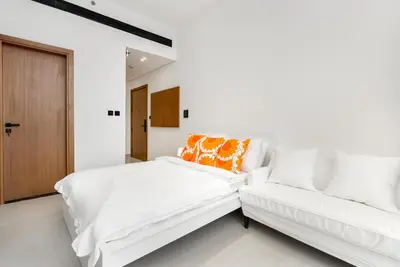 a white bedroom with a bed and a couch at Cozy Studio with Sleek Design in JVC in Dubai