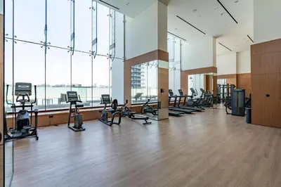 a gym with a lot of treadmills and ellipticals at Cozy Studio with Sleek Design in JVC in Dubai