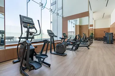 a gym with a row of treadmills and ellipticals at Cozy Studio with Sleek Design in JVC in Dubai