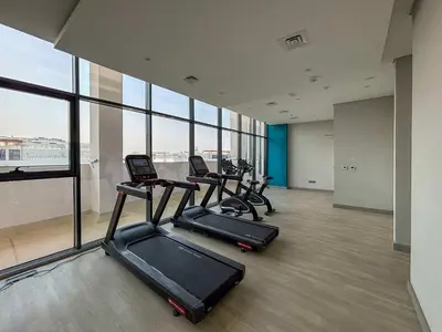 a gym with three treadmills in a room with windows at Frank Porter - Azizi Riviera 28 in Dubai