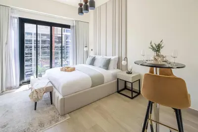 a white bedroom with a bed and a table at Frank Porter - Azizi Riviera 28 in Dubai