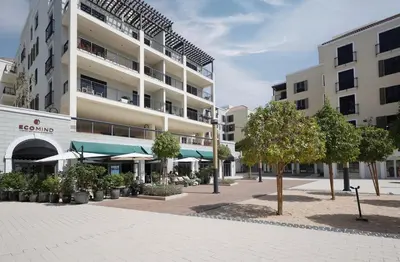 an apartment building with a courtyard with trees and umbrellas at Elite LUX Holiday Homes - 1BHK Beachside Retreat at Port De La Mer, Dubai in Dubai