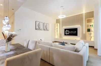 a living room with a white couch and a table at Elite LUX Holiday Homes - 1BHK Beachside Retreat at Port De La Mer, Dubai in Dubai