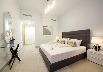 a white bedroom with a large bed and a mirror at Stylish 2BR in Bellevue Pool, Gym & Burj Views in Dubai
