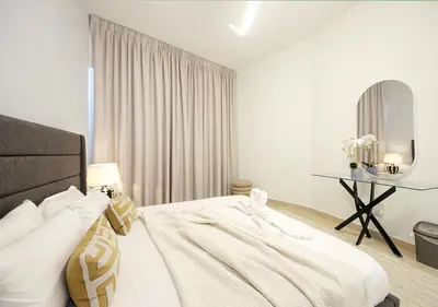 a white bedroom with a bed and a table at Stylish 2BR in Bellevue Pool, Gym & Burj Views in Dubai